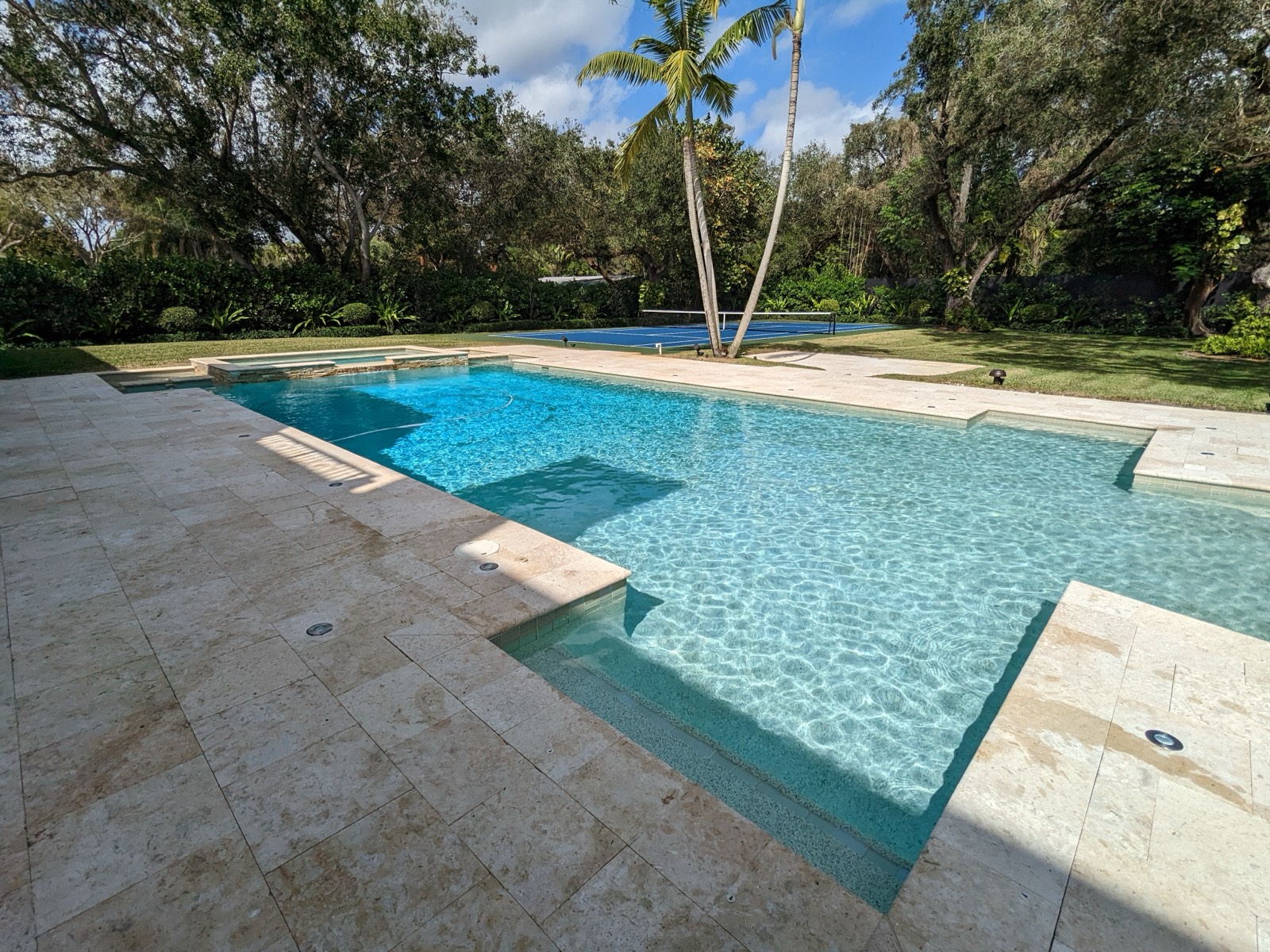 Large estate pool with attached spa, travertine deck, and sport court