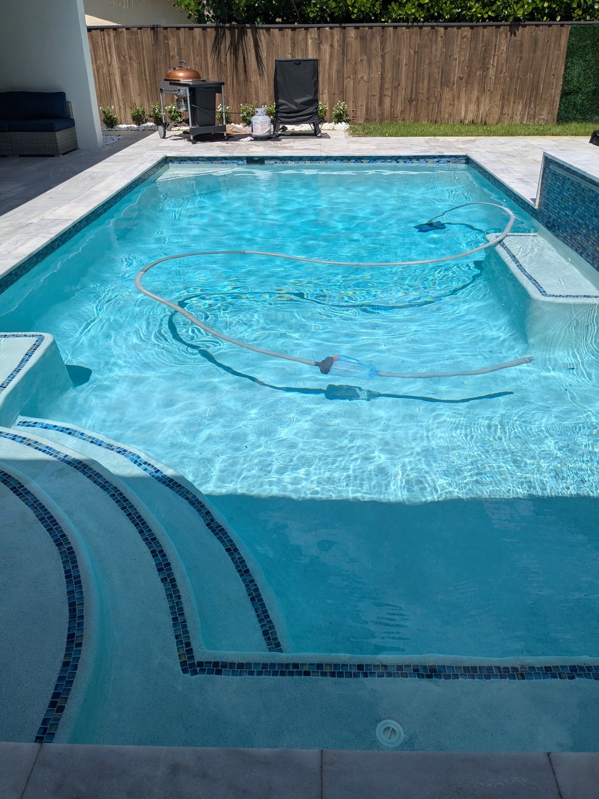 Pool cleaning equipment and vacuum hose in a clear blue pool mid-service